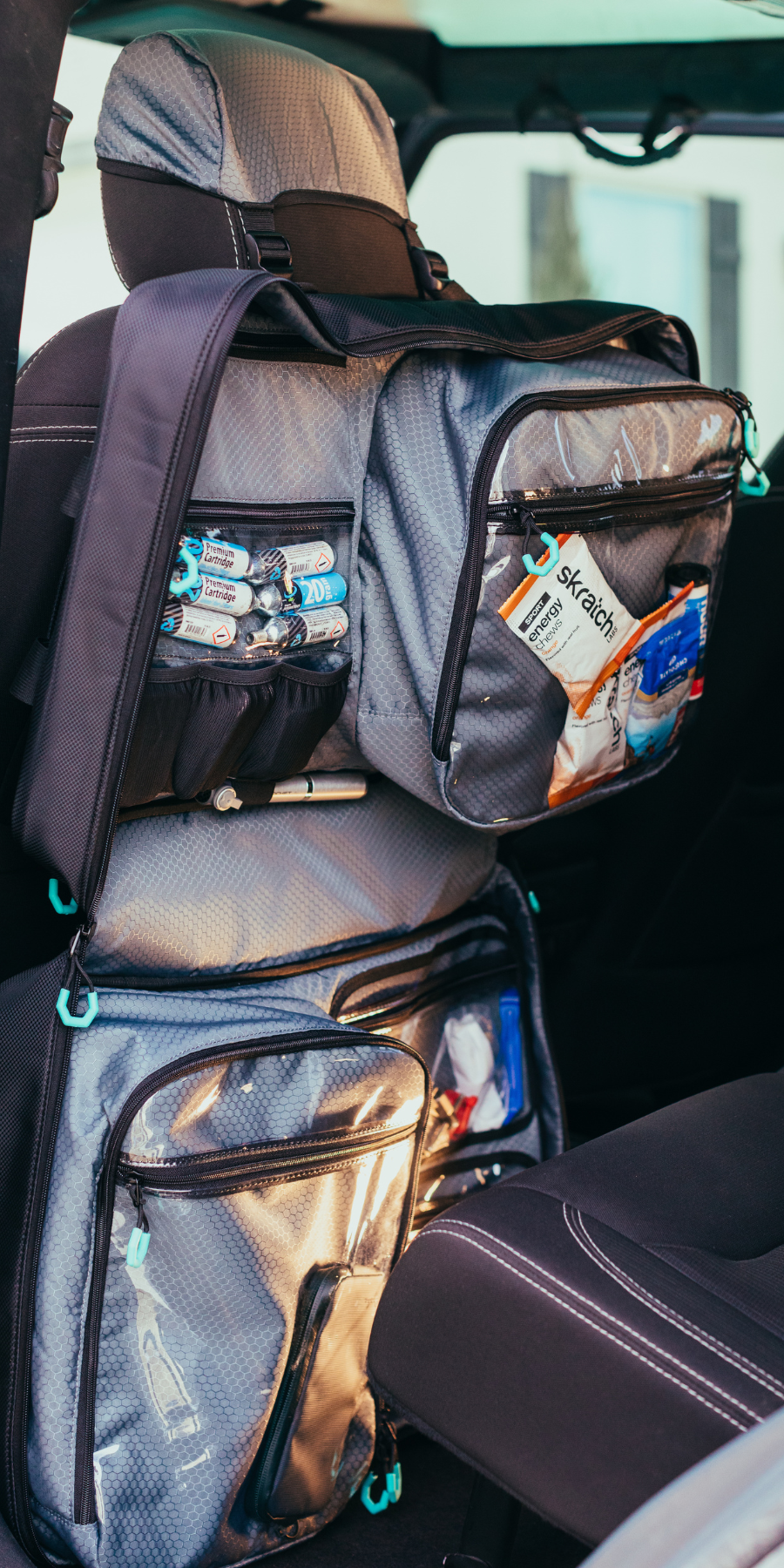 Parc cycling gear bag hanging in car on back of driver seat. Cycling bag hangs from headrest hood. Cycling bag contents visible.