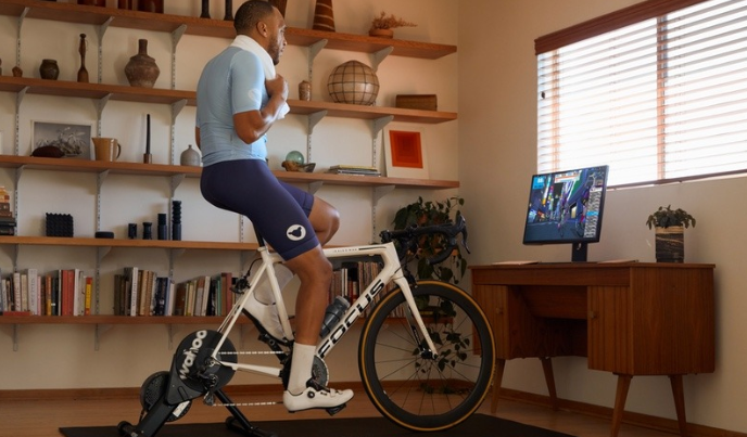 Man on indoor cycling trainer looking at computer