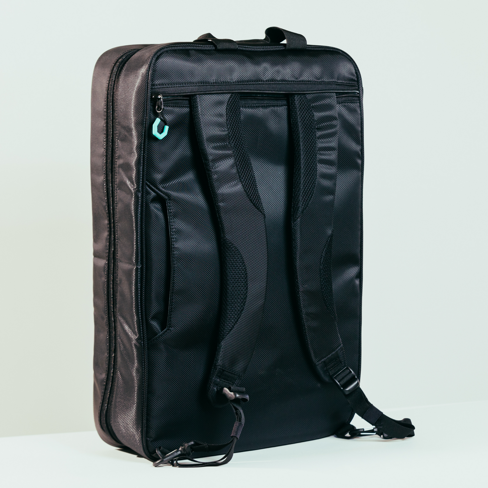 Parc cycling gear bag zipped up and standing upright in front of a road bike. A black bike gear bag with turquoise Parc logo and zipper pulls and black reflective stripes.